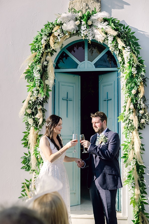 Ρομαντικός στολισμός εισόδου εκκλησίας με πλούσια γιρλάντα πρασινάδας, λευκά τριαντάφυλλα και pampas grass