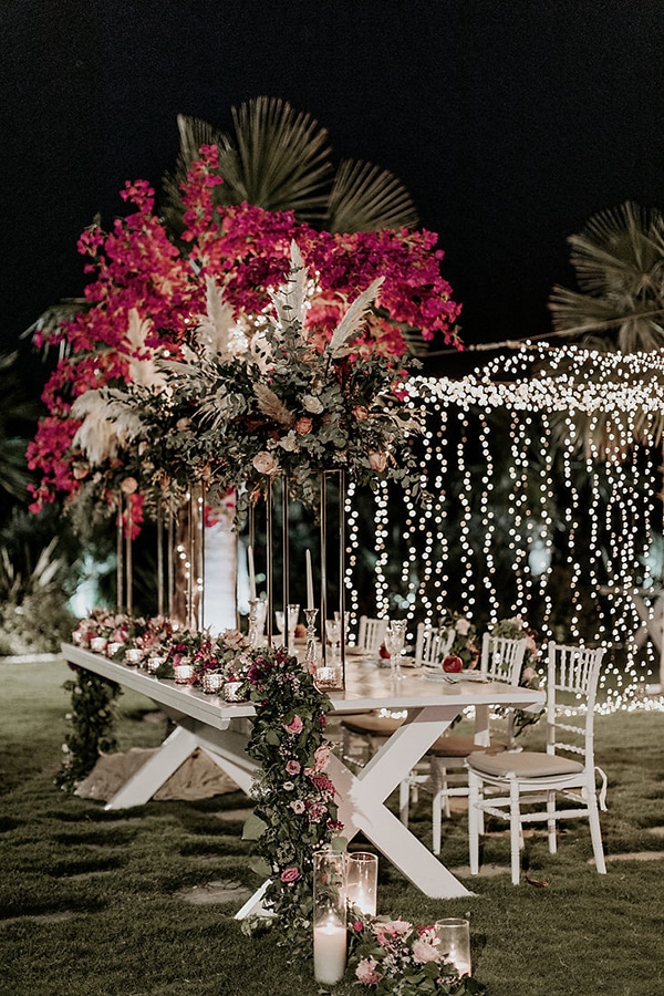 Στολισμός γαμήλιου τραπεζιού με πλούσιες γιρλάντες από άνθη σε φούξια και ροζ τόνους