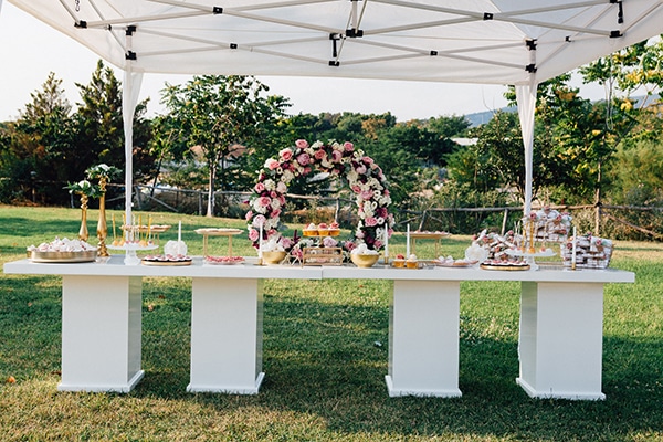 Dessert table σε λευκό χρώμα με κυκλική αψίδα λουλουδιών
