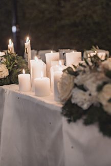 Ατμοσφαιρικός στολισμός γαμήλιου τραπεζιού με λευκά κεριά και λουλούδια