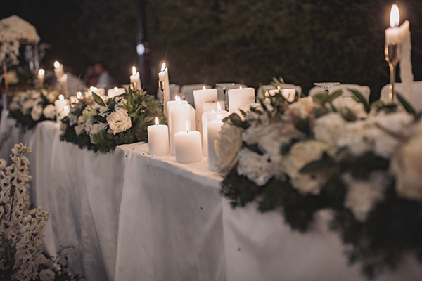 Ατμοσφαιρικός στολισμός γαμήλιου τραπεζιού με λευκά κεριά και λουλούδια