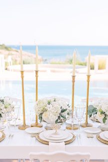 Elegant στολισμός γαμήλιου τραπεζιού με λευκά μπουκετάκια και χρυσά κεριά