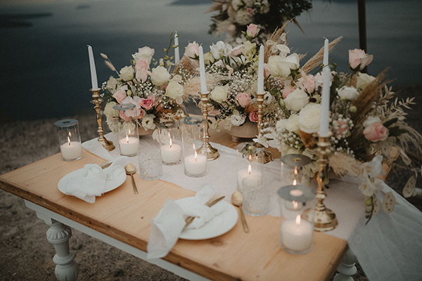 Ρομαντικός στολισμός γαμήλιου τραπεζιού με λευκά κεριά και λουλούδια