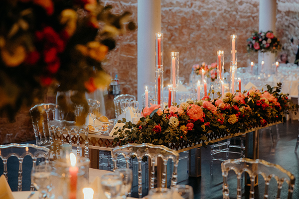 Ατμοσφαιρικός στολισμός γαμήλιου τραπεζιού με πολύχρωμα λουλούδια και κεριά
