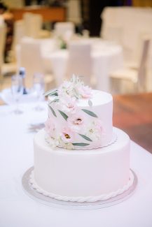 Λευκή τούρτα γάμου δύο ορόφων με φρέσκα λουλούδια