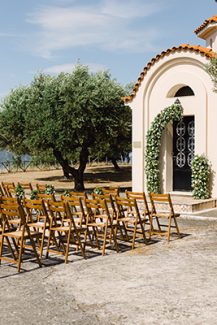 Ρουστίκ στολισμός τελετής γάμου με ξύλινες καρέκλες και διακοσμητική αψίδα απο φύλλα ελιάς
