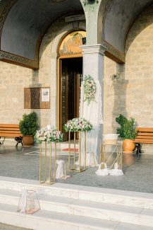 Όμορφος στολισμός εισόδου εκκλησίας με χρυσά stand και λουλούδια