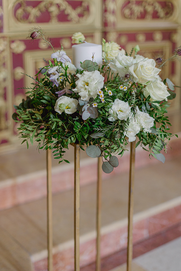 Διακόσμηση γαμήλιας λαμπάδας πάνω σε χρυσό stand με λευκά άνθη