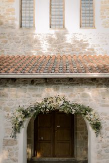 Ρομαντικός στολισμός εισόδου εκκλησίας με γιρλάντα λουλουδιών σε παστέλ αποχρώσεις