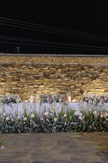Διακόσμηση γαμήλιου τραπεζιού πλημμυρισμένο από όμορφα τριαντάφυλλα και λευκό λυσίανθο