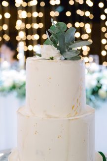 Διώροφη γαμήλια τούρτα με πορτοκαλί πινελιές και cake topper από λουλούδια