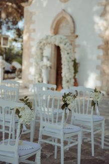 Total white διακόσμηση τελετής γάμου με λουλουδένια αψίδα
