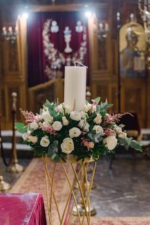 Όμορφη διακόσμηση γαμήλιας λαμπάδας με τριαντάφυλλα πάνω σε χρυσή βάση