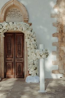 Στολισμός εισόδου εκκλησίας λευκή λουλουδένια αψίδα