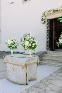 Πλούσιος στολισμός γαμήλιας λαμπάδας με λευκές ορτανσίες και τριαντάφυλλα