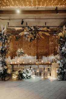 Εντυπωσιακός στολισμός γαμήλιου τραπεζιού με αψίδα λουλουδιών και κεριά